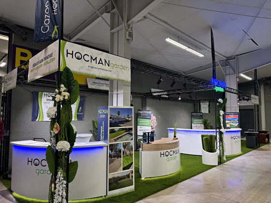 Stand Hocman Garden sur un salon : comptoirs blancs et sol en gazon synthétique