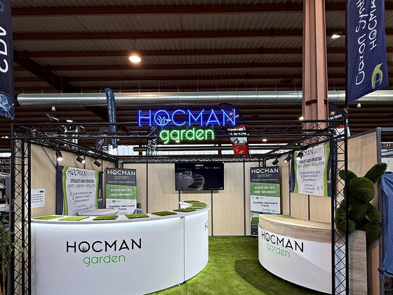 Enseigne néon Hocman Garden au-dessus du stand d'un salon